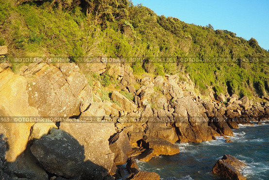Waves gently crash against the rugged rocks while the sun sets over the horizon. Experience the serene beauty of this coastal location filled with natural wonders. Canj, Montenegro, Adriatic sea (2024 год). Стоковое фото, фотограф Юлия Петровская / Фотобанк Лори