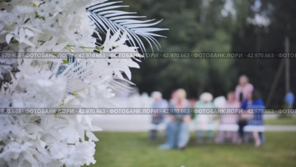 Wedding arch flowers in the background of the guests waiting for the wedding registration in nature. Стоковое видео, видеограф Mikhail Davidovich / Фотобанк Лори