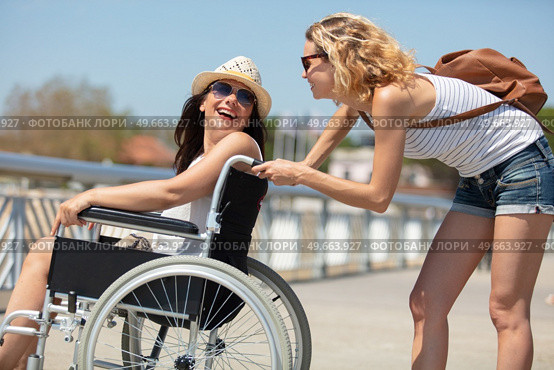 wheelchair bound blonde smiling with her friend. Стоковое фото, агентство Ingram Publishing / Фотобанк Лори