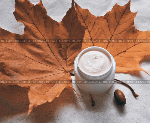 White jar with oily cream for cold weather against a background of red maple leaves. Стоковое фото, фотограф burnet / Фотобанк Лори