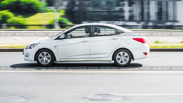 White sedan Hyundai Solaris Accent fast speed driving on the asphalt road. Редакционное фото, фотограф Константин Григорьев / Фотобанк Лори
