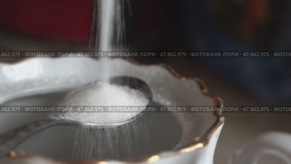White sugar pouring into elegant tea cup with spoon. Стоковое видео, видеограф Андрей Знаменский / Фотобанк Лори