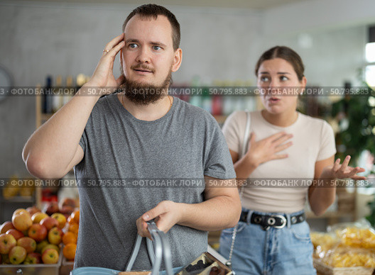 Wife stands behind husband and yells at companion in shop. Стоковое фото, фотограф Яков Филимонов / Фотобанк Лори