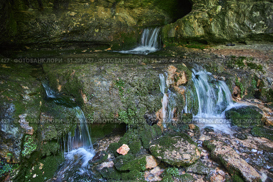 Wild cave outside. The river flows out of the cave, a waterfall. Speleology and surveys. Стоковое фото, фотограф Наталия Кирсанова / Фотобанк Лори