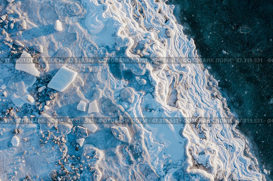 Winter aerial photograph of the icy coast and ice floes in sea water. Top view of the freezing sea. Nature of the Extreme North. Cold frosty winter weather. Harsh arctic climate. Natural background. Стоковое фото, фотограф Андрей Степанов / Фотобанк Лори