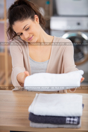 woman adding towel to clean folded pile. Стоковое фото, агентство Ingram Publishing / Фотобанк Лори