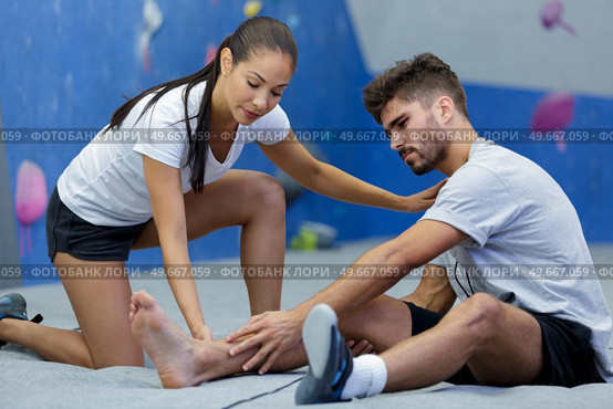 woman assisting climber with injury in the ankle. Стоковое фото, агентство Ingram Publishing / Фотобанк Лори