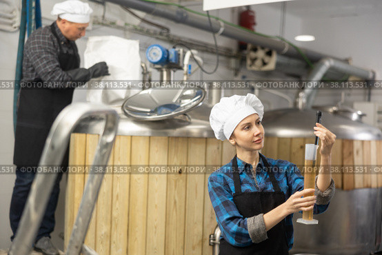 Woman brewmaster measuring beer sample with alcoholometer. Стоковое фото, фотограф Яков Филимонов / Фотобанк Лори