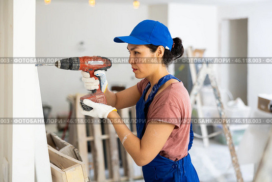Woman builder using drill to bore hole in wall. Стоковое фото, фотограф Яков Филимонов / Фотобанк Лори