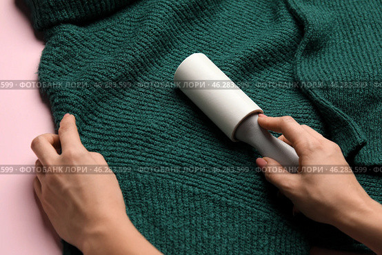 Woman cleaning green sweater with lint roller, closeup. Стоковое фото, фотограф Pixel_shot / Фотобанк Лори