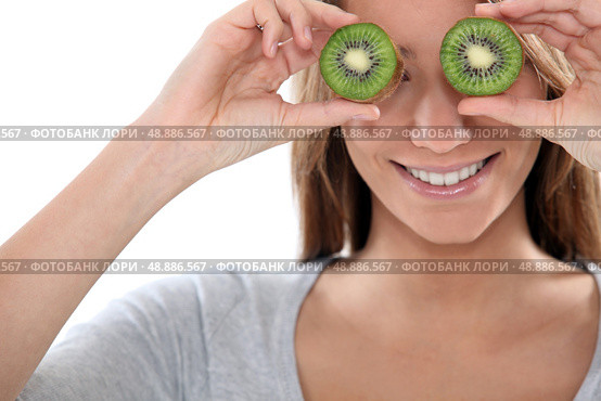 Woman covering her eyes with slices of kiwi. Стоковое фото, агентство Ingram Publishing / Фотобанк Лори