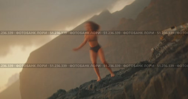Woman dancing with graceful body movements on rocky shore at golden hour. Стоковое видео, видеограф Igor Tichonow / Фотобанк Лори