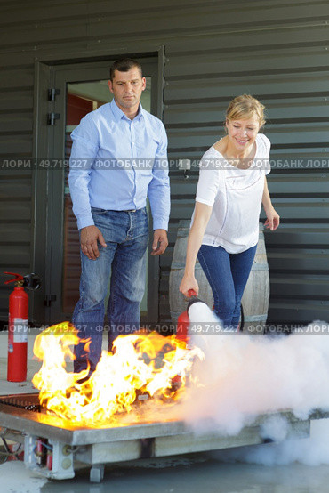 woman demonstrating how to use a fire extinguisher. Стоковое фото, агентство Ingram Publishing / Фотобанк Лори