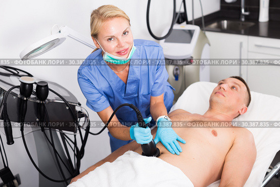 Woman doctor is doing vacuum massage procedure on belly of adult client. Стоковое фото, фотограф Яков Филимонов / Фотобанк Лори