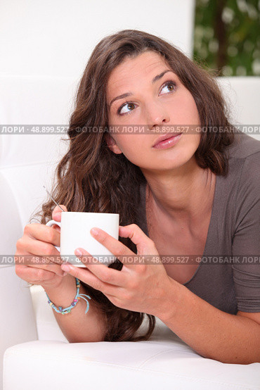 Woman drinking a coffee on a sofa. Стоковое фото, агентство Ingram Publishing / Фотобанк Лори