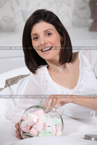 Woman eating marshmallows in bed. Стоковое фото, агентство Ingram Publishing / Фотобанк Лори