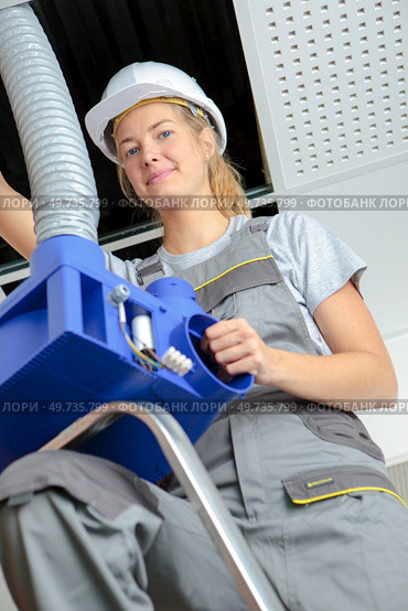 Woman fitting pipework into roofspace. Стоковое фото, агентство Ingram Publishing / Фотобанк Лори