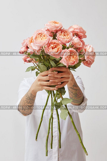 woman holding a bouquet made from fresh pink roses on a gray background, valentine’s day, mother’s day. the girl is holding a bouquet of fresh pink roses, Стоковое фото, агентство Ingram Publishing / Фотобанк Лори