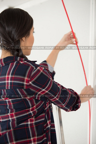woman in a plaid-shirt lining the walls in her apartment. Стоковое фото, агентство Ingram Publishing / Фотобанк Лори