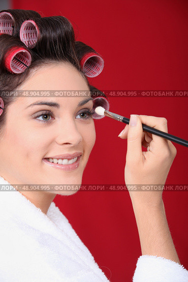 Woman in curlers applying eyeshadow. Стоковое фото, агентство Ingram Publishing / Фотобанк Лори