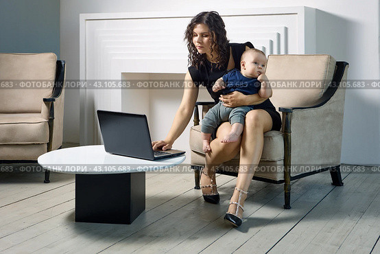 Woman in maternity leave works remotely, with child on his knees. Стоковое фото, фотограф Владимир Григорьев / Фотобанк Лори