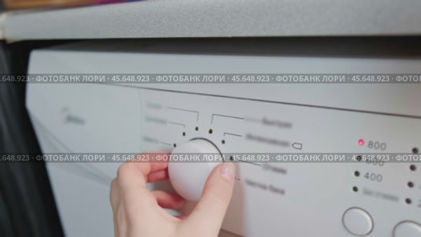 Woman in orange apron turns on washing machine, modern washing machines with smart features and functions. Стоковое видео, видеограф Svetlana Golovco / Фотобанк Лори
