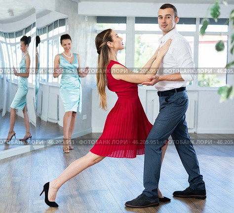 Woman in red and man in formal wear rehearsing tango in pair. Стоковое фото, фотограф Яков Филимонов / Фотобанк Лори