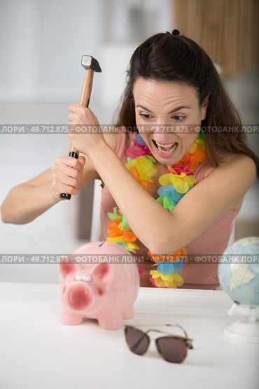 woman is smashing piggy bank with hammer. Стоковое фото, агентство Ingram Publishing / Фотобанк Лори