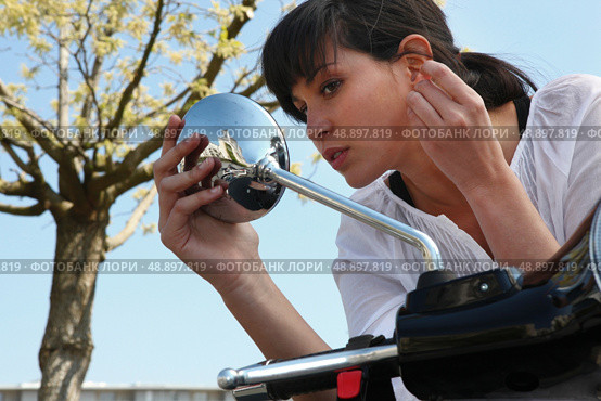 Woman looking in rearview mirror of a scooter. Стоковое фото, агентство Ingram Publishing / Фотобанк Лори