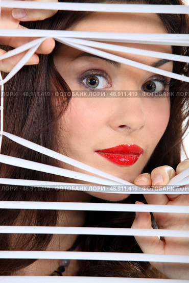 woman looking through window blinds. Стоковое фото, агентство Ingram Publishing / Фотобанк Лори