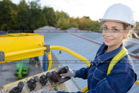 woman maneuvering cherry picker above warehouses. Стоковое фото, агентство Ingram Publishing / Фотобанк Лори