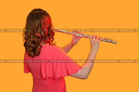 Woman musician with a flute on a studio yellow background. Flutist with a large concert transverse flute, close up. Стоковое фото, фотограф Андрей Журавлев / Фотобанк Лори