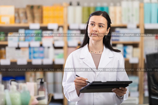 Woman pharmacist makes restock, uses electronic carrier tablet of information. Стоковое фото, фотограф Яков Филимонов / Фотобанк Лори