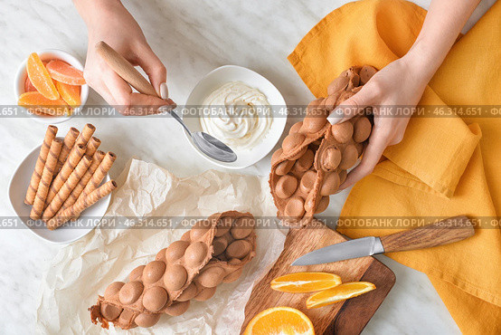 Woman preparing sweet bubble waffles at table, top view. Стоковое фото, фотограф Pixel_shot / Фотобанк Лори