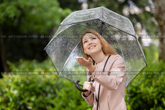 woman rainy girl with transparent umbrella holds out her hand. Стоковое фото, агентство Ingram Publishing / Фотобанк Лори