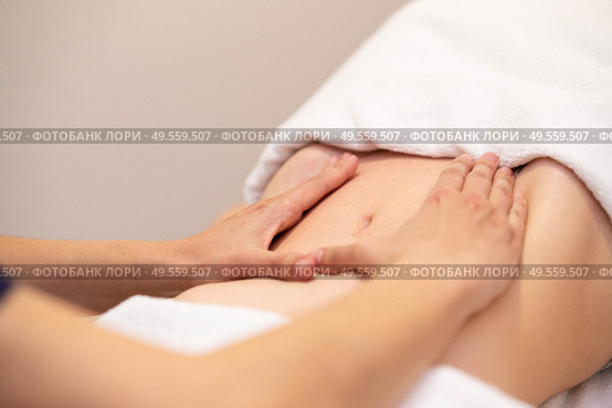 Woman receiving a belly massage at spa salon. Female patient is receiving treatment by professional osteopathy therapist.. Woman receiving a belly massage at spa salon. Стоковое фото, агентство Ingram Publishing / Фотобанк Лори