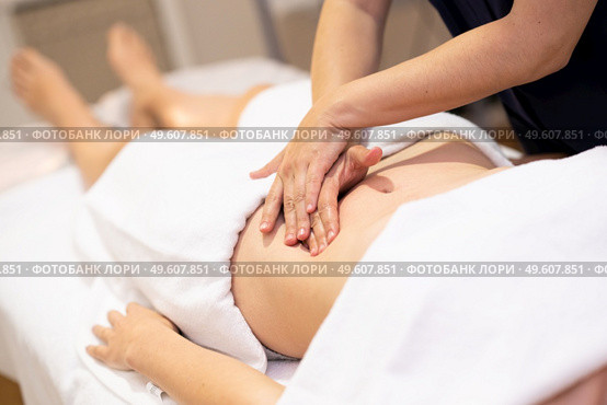 Woman receiving a belly massage in a physiotherapy center. Female patient is receiving treatment by professional osteopathy therapist.. Woman receiving a belly massage in a physiotherapy center. Стоковое фото, агентство Ingram Publishing / Фотобанк Лори