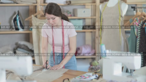 Woman seamstress cutting fabric in sewing workshop. Стоковое видео, видеограф Яков Филимонов / Фотобанк Лори