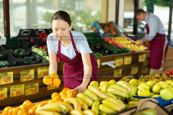 Woman selelr of vegetable department store is replenishing showcase with oranges. Стоковое фото, фотограф Яков Филимонов / Фотобанк Лори