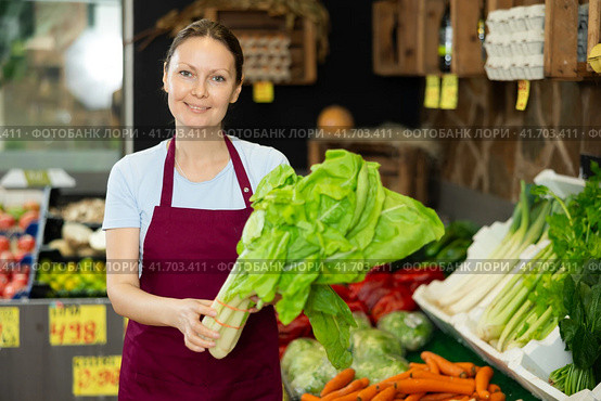 Woman seller of garden stuff store replenishing showcase, puts salad mangold on showcase. Стоковое фото, фотограф Яков Филимонов / Фотобанк Лори