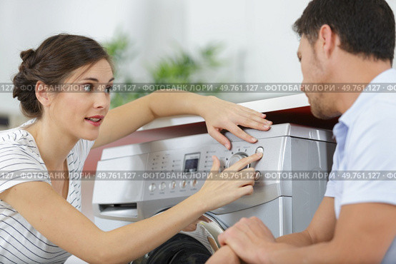 woman showing husband defects in washing machine. Стоковое фото, агентство Ingram Publishing / Фотобанк Лори