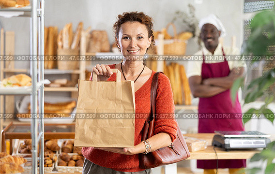 Woman showing paper bag with delicious pastries bought from bakery. Стоковое фото, фотограф Яков Филимонов / Фотобанк Лори