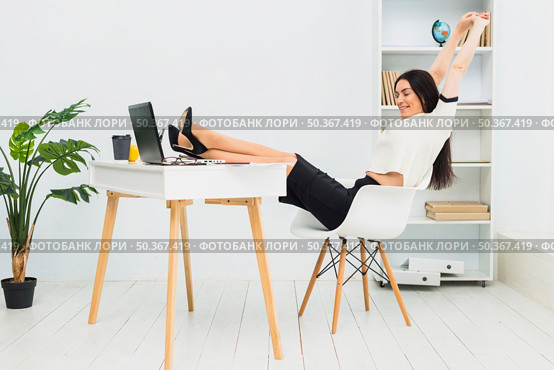 woman stretching arms sitting table office. Стоковое фото, агентство Ingram Publishing / Фотобанк Лори