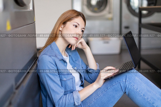 woman using the pc at the laundry. Стоковое фото, агентство Ingram Publishing / Фотобанк Лори