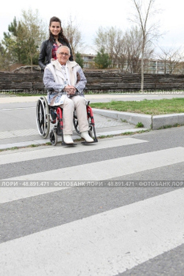 Woman waiting at a zebra crossing with an elderly lady in a wheelchair. Стоковое фото, агентство Ingram Publishing / Фотобанк Лори