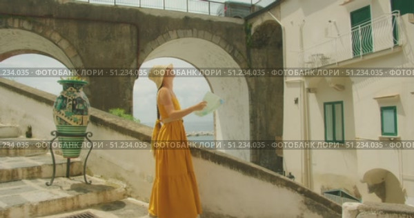 Woman walking and reading map on seaside staircase near large vase and stone arched bridge in summer. Стоковое видео, видеограф Ольга Сухарева / Фотобанк Лори