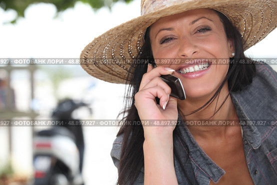 Woman wearing a straw hat talking on her mobile phone. Стоковое фото, агентство Ingram Publishing / Фотобанк Лори