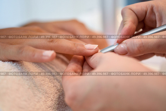 Woman with deteriorated nails in a salon receiving a manicure by a beautician with nail file. Стоковое фото, агентство Ingram Publishing / Фотобанк Лори