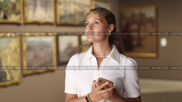 Woman with phone in hands view pictures and icons in museum hall. Стоковое видео, видеограф Яков Филимонов / Фотобанк Лори