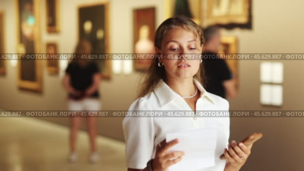 Woman with sheet piece of paper in hands view pictures and icons in museum hall. Стоковое видео, видеограф Яков Филимонов / Фотобанк Лори